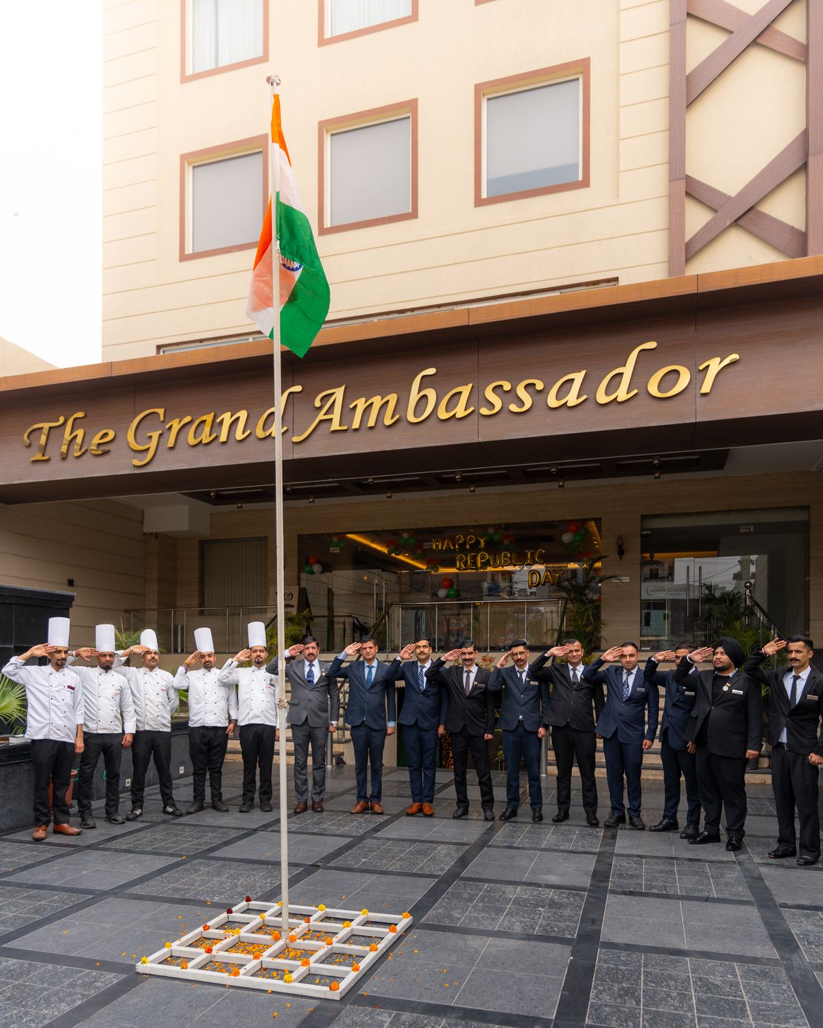 The team of The Grand Ambassador at the flag, under the hotel's signage on Railway Road