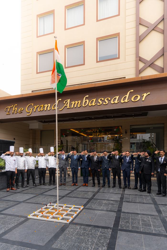 The team of The Grand Ambassador at the flag, under the hotel's signage on Railway Road