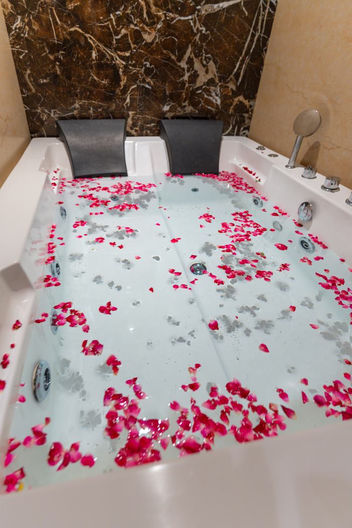 A bed turned down under rose petals