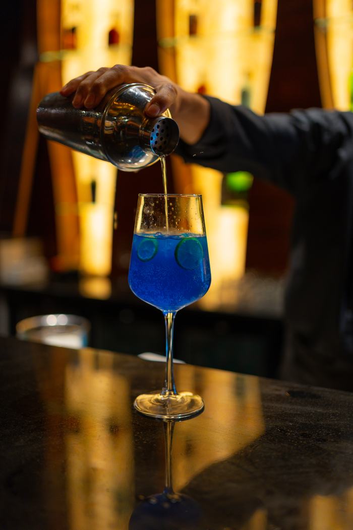 A blue cocktail poured at the counter