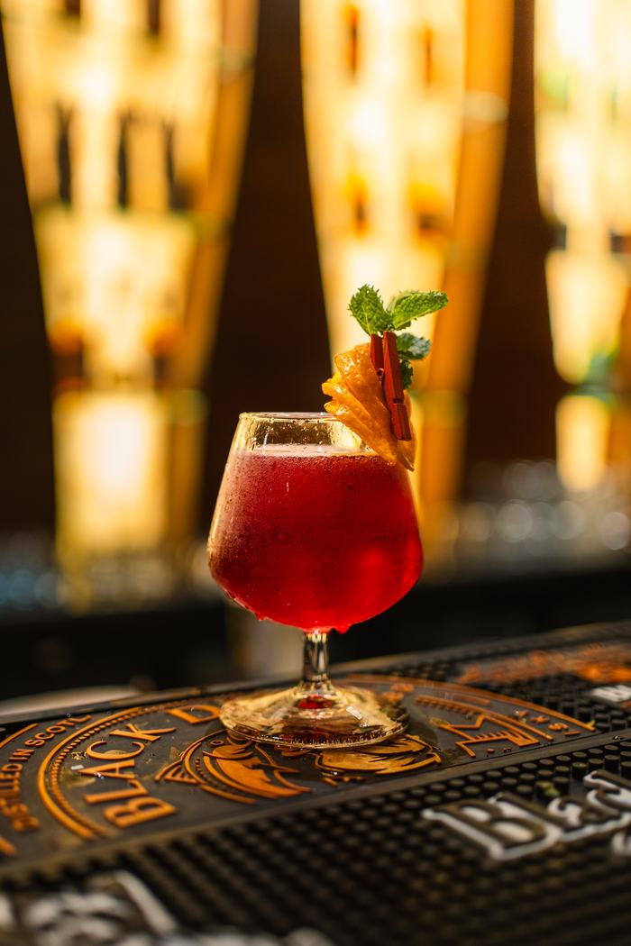 A long red cocktail against the bottle wall