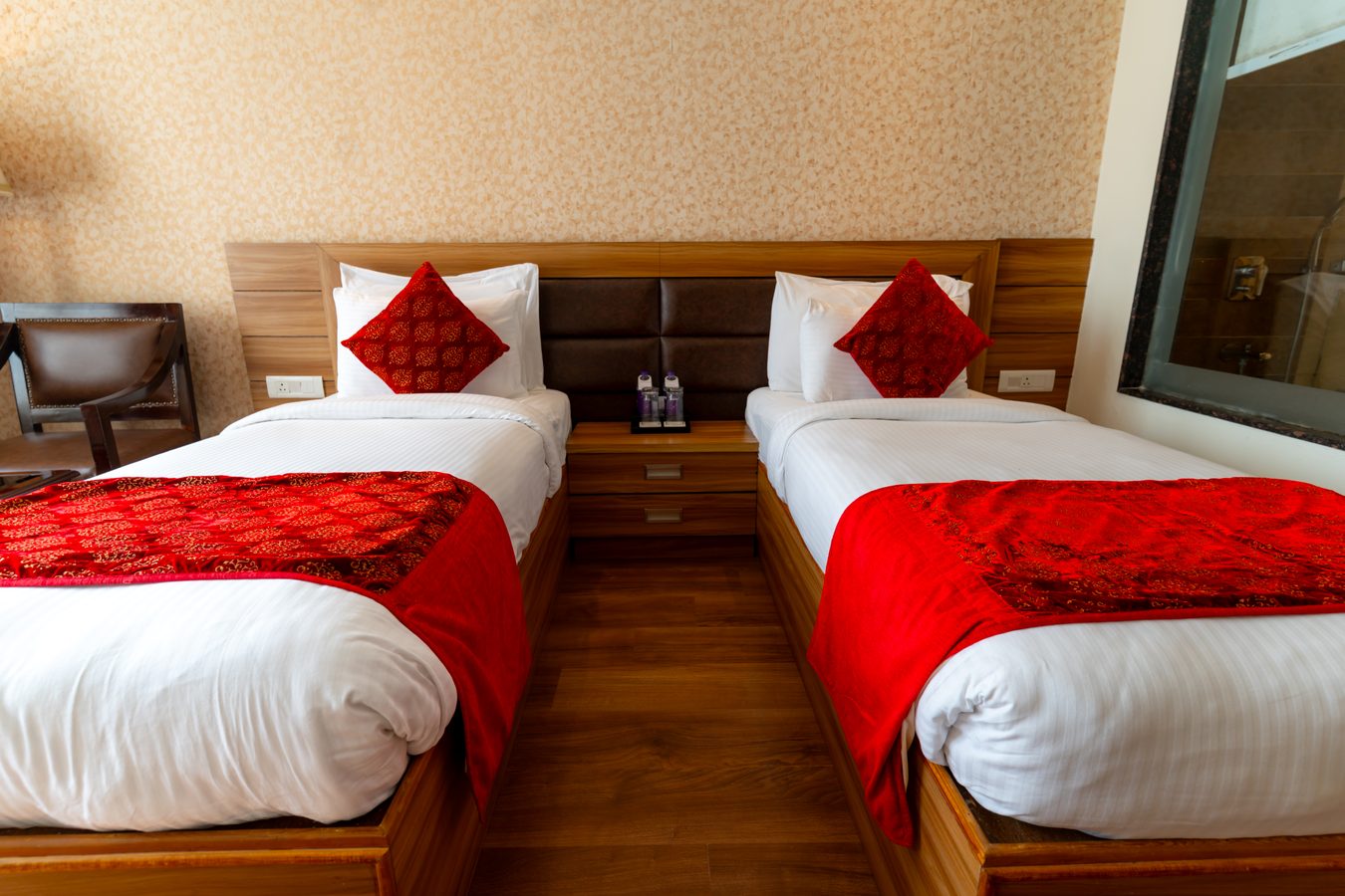 A Twin Room in bright daylight, red runners on both beds